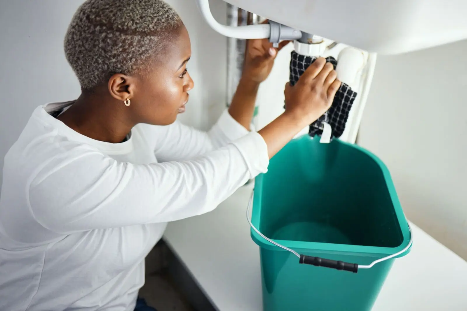 Plumbing, water and a black woman in the bathroom of her home with a cloth and bucket waiting for a Plumbing, water and a black woman in the bathroom of her home with a cloth and bucket waiting for a