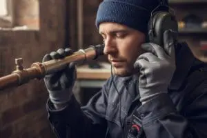 Technician using acoustic listening equipment to pinpoint a leak in a copper pipe