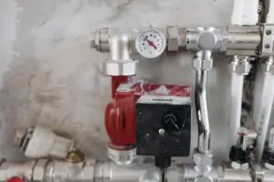 Commercial boiler and heating pipework with pressure gauge in a business plant room